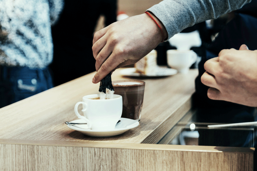 pouring sugar from stick pack package into coffee